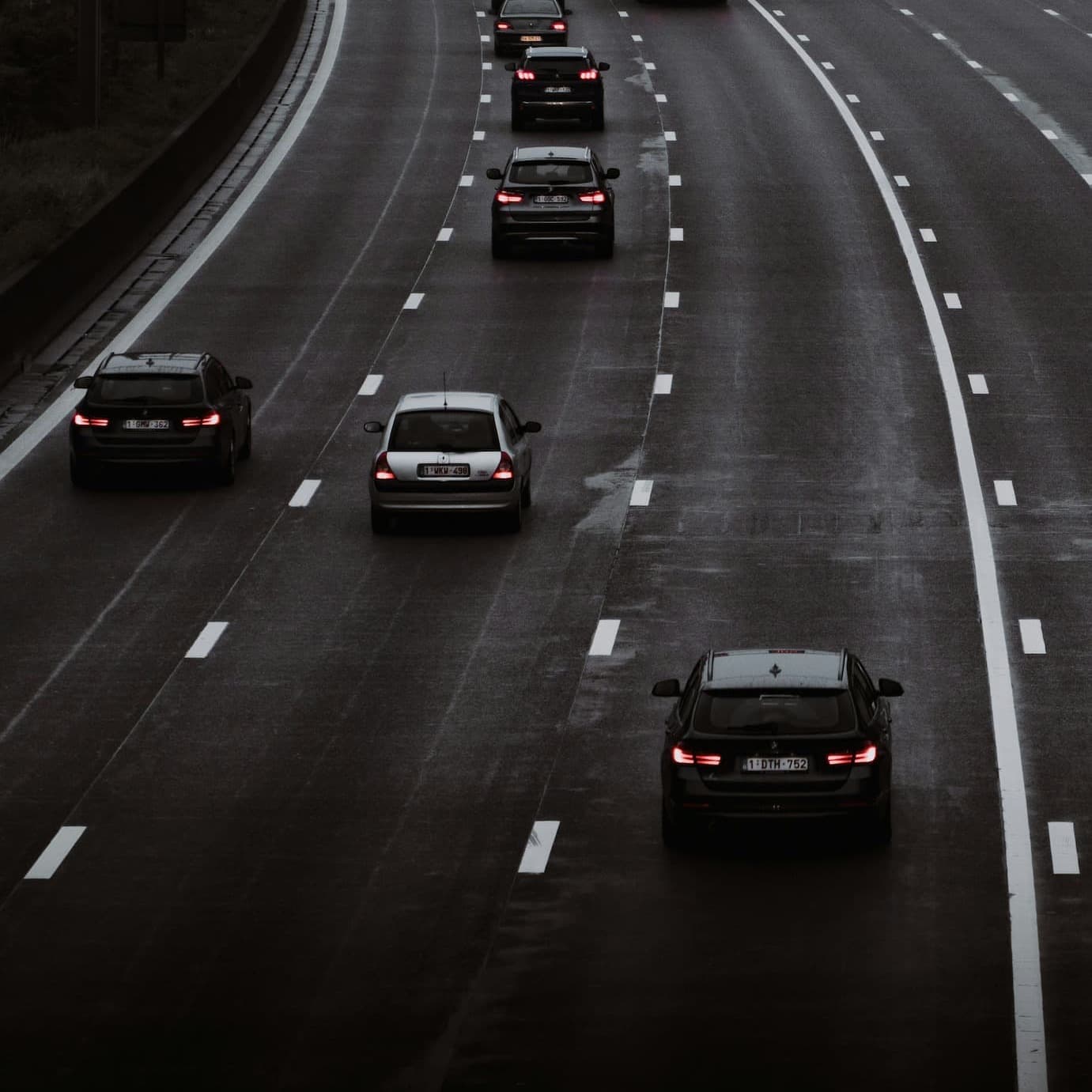 Widok ruchu na autostradzie z kilkoma samochodami jadącymi po mokrej nawierzchni.