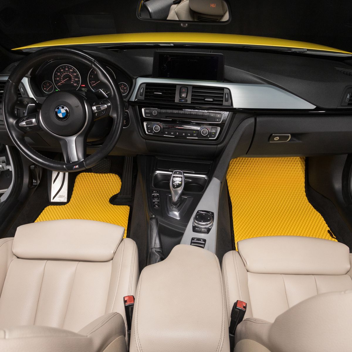 Żółte maty EVA w luksusowym wnętrzu samochodu BMW, skórzane fotele i nowoczesny design.