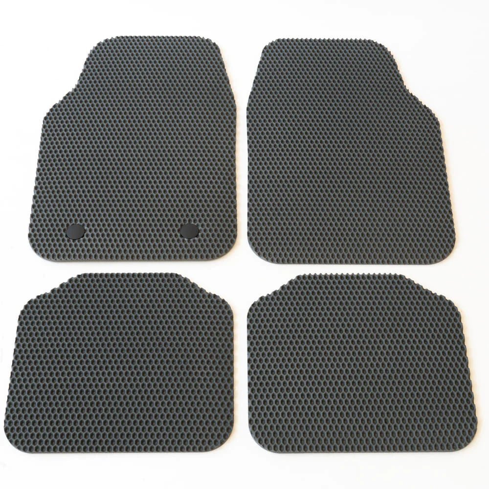 Cztery czarne mata podłogowe z wytrzymałego materiału o strukturze plastra miodu.