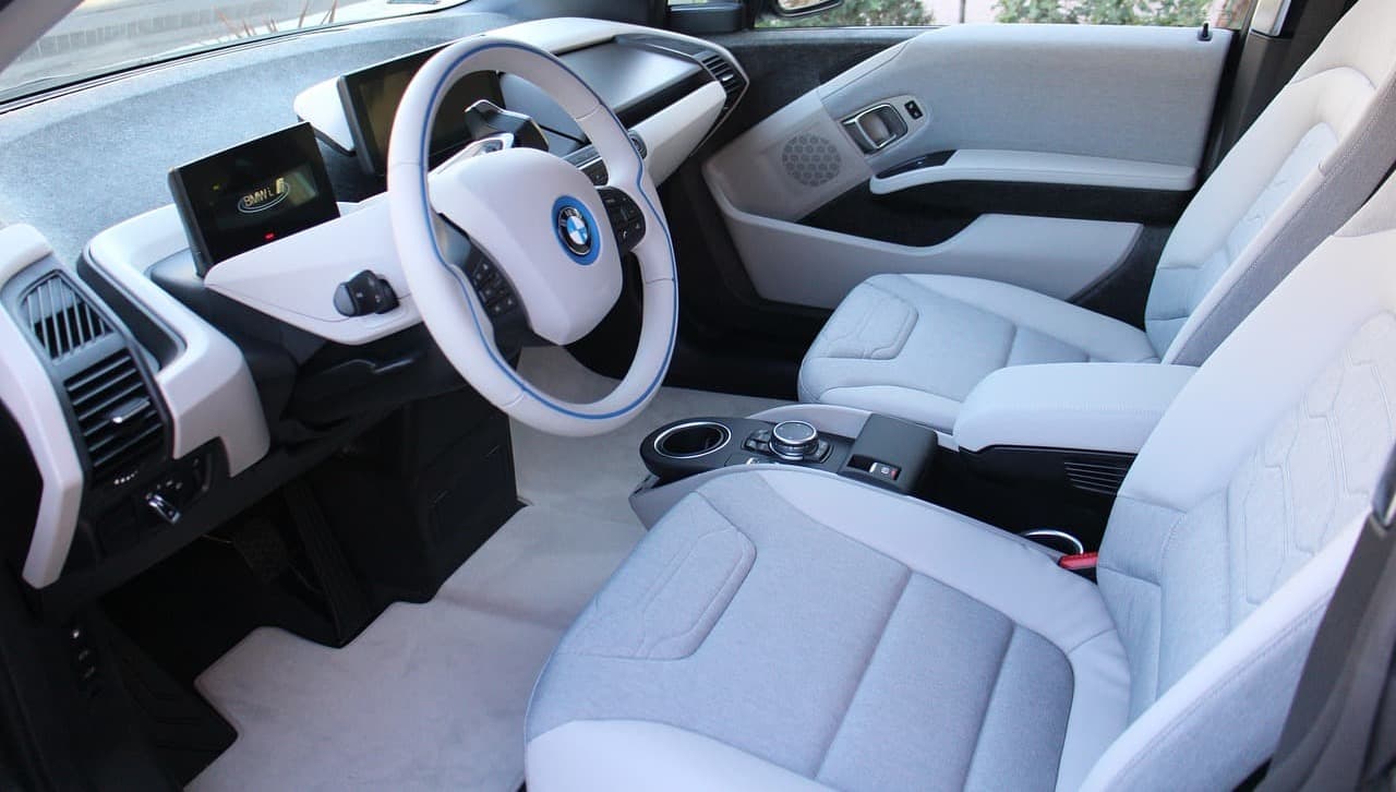 Nowoczesne wnętrze BMW z jasną tapicerką i dwoma ekranami na desce rozdzielczej.