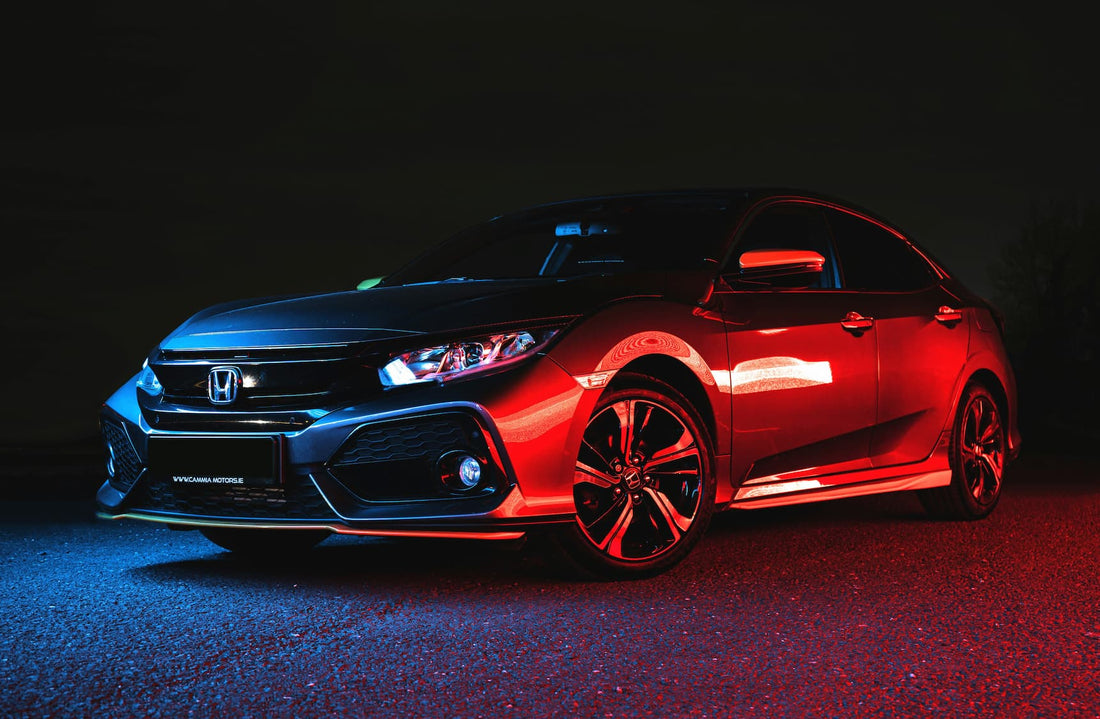 Honda Civic nocą z czerwonym i niebieskim oswietleniem podkreslajacym sportowy wyglad auta.