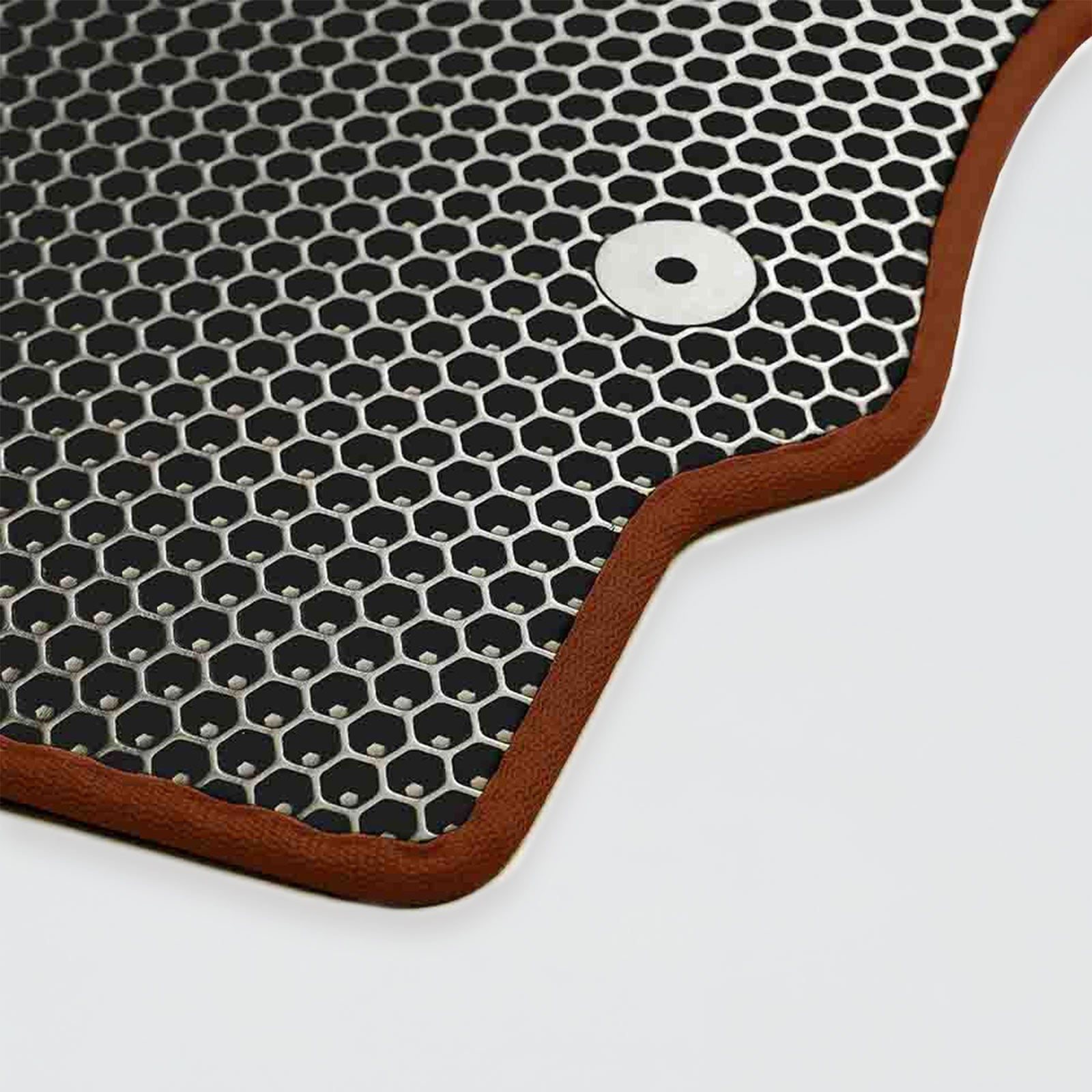 A black hexagonal patterned mat with a brown border and a metal hole.