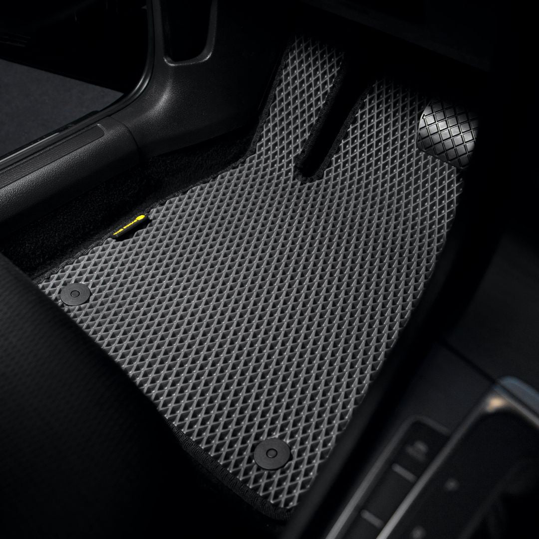 Niestandardowa czarna teksturowana mata podłogowa do samochodu we wnętrzu nowoczesnego pojazdu.